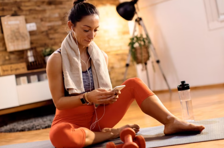 female athlete using smart phone while relaxing on the floor at home