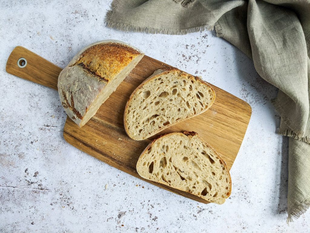 Sliced loaf of crusty bread on a wooden cutting board