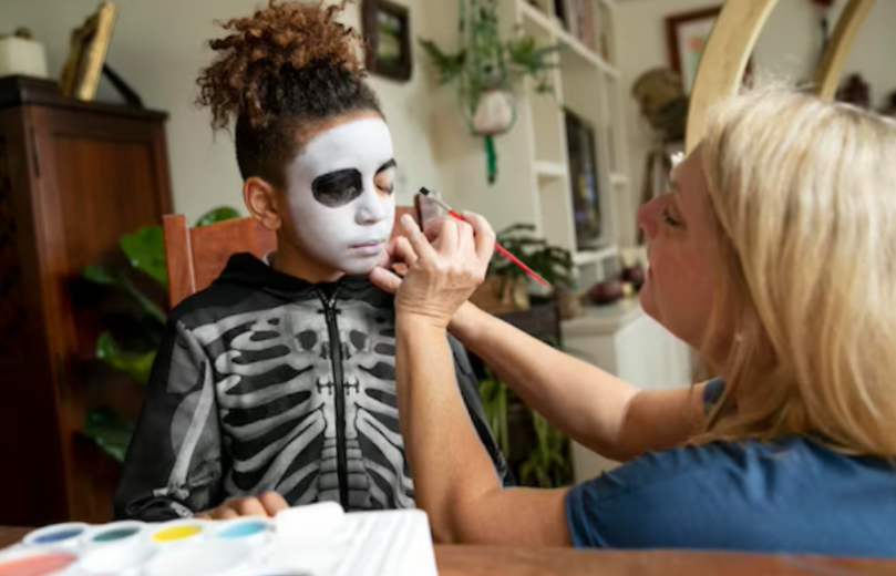 ittle girl preparing for halloween with a skeleton costume