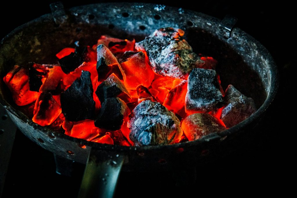 Glowing hot charcoal with gray ash in a round metal grill