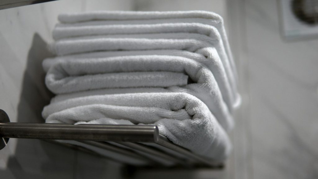A stack of folded white towels on a metal towel rail