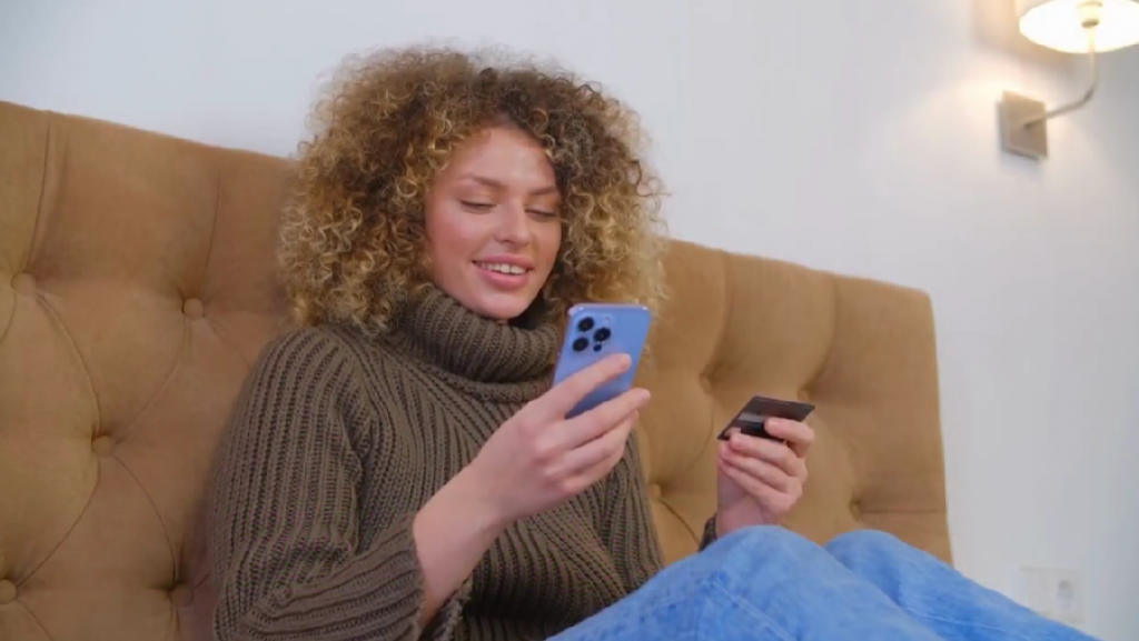 Woman sitting in an armchair with card and cell phone in hand