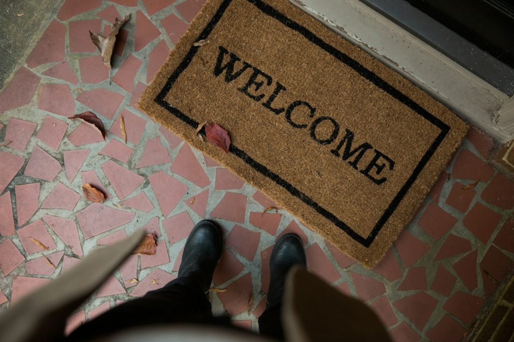 Coir welcome mat on a tiled porch with fallen leaves