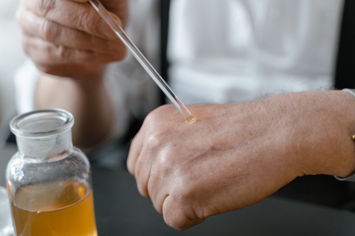 Stock photo of a hand testing a fragrance with a glass dropper. Not a listed product.