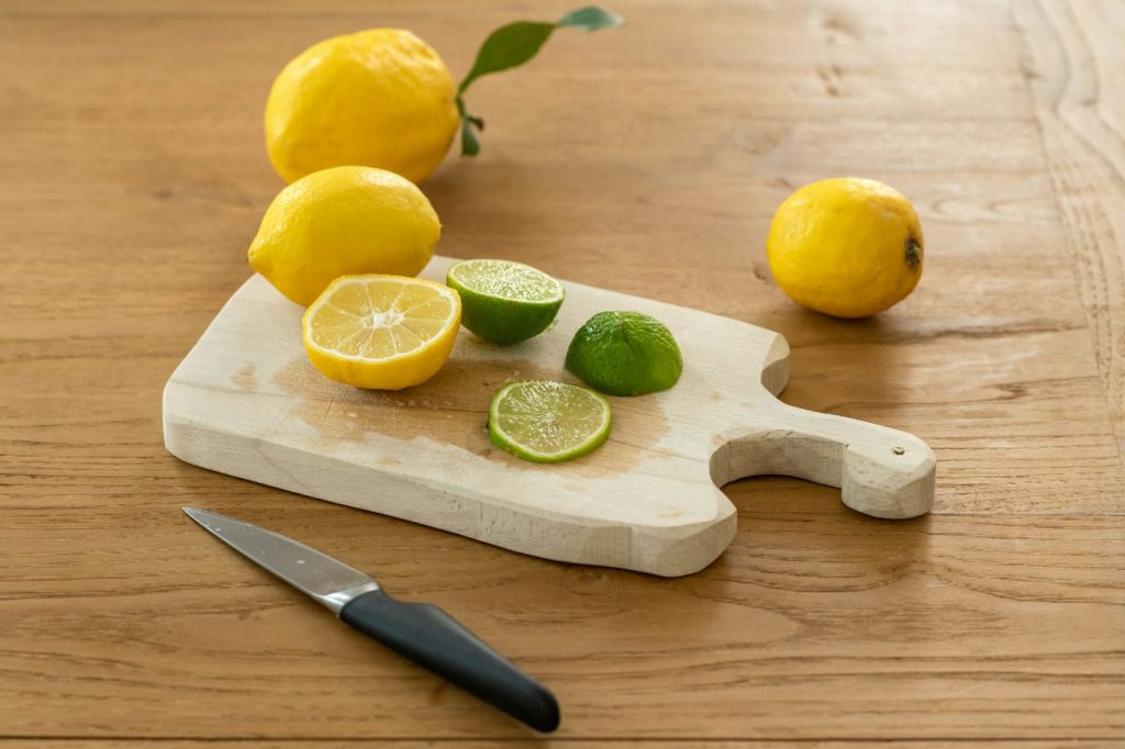 Sliced lemons and limes with a knife on a small wooden cutting board