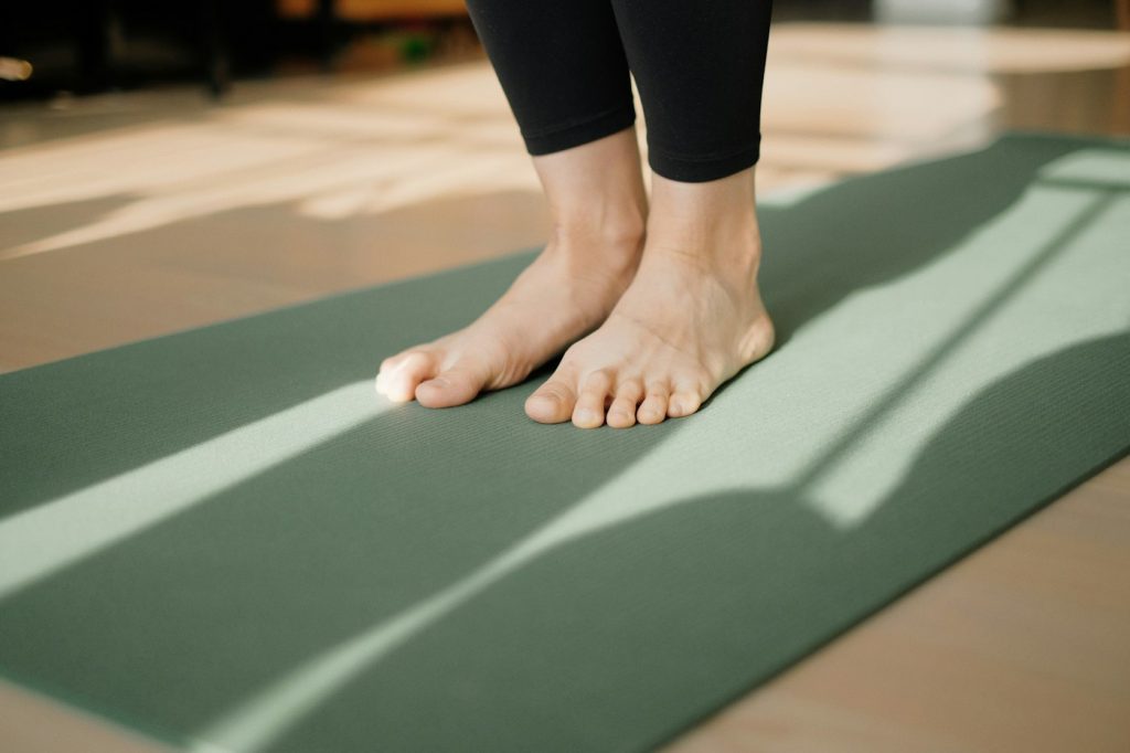 Bare feet on a green yoga mat in warm sunlight