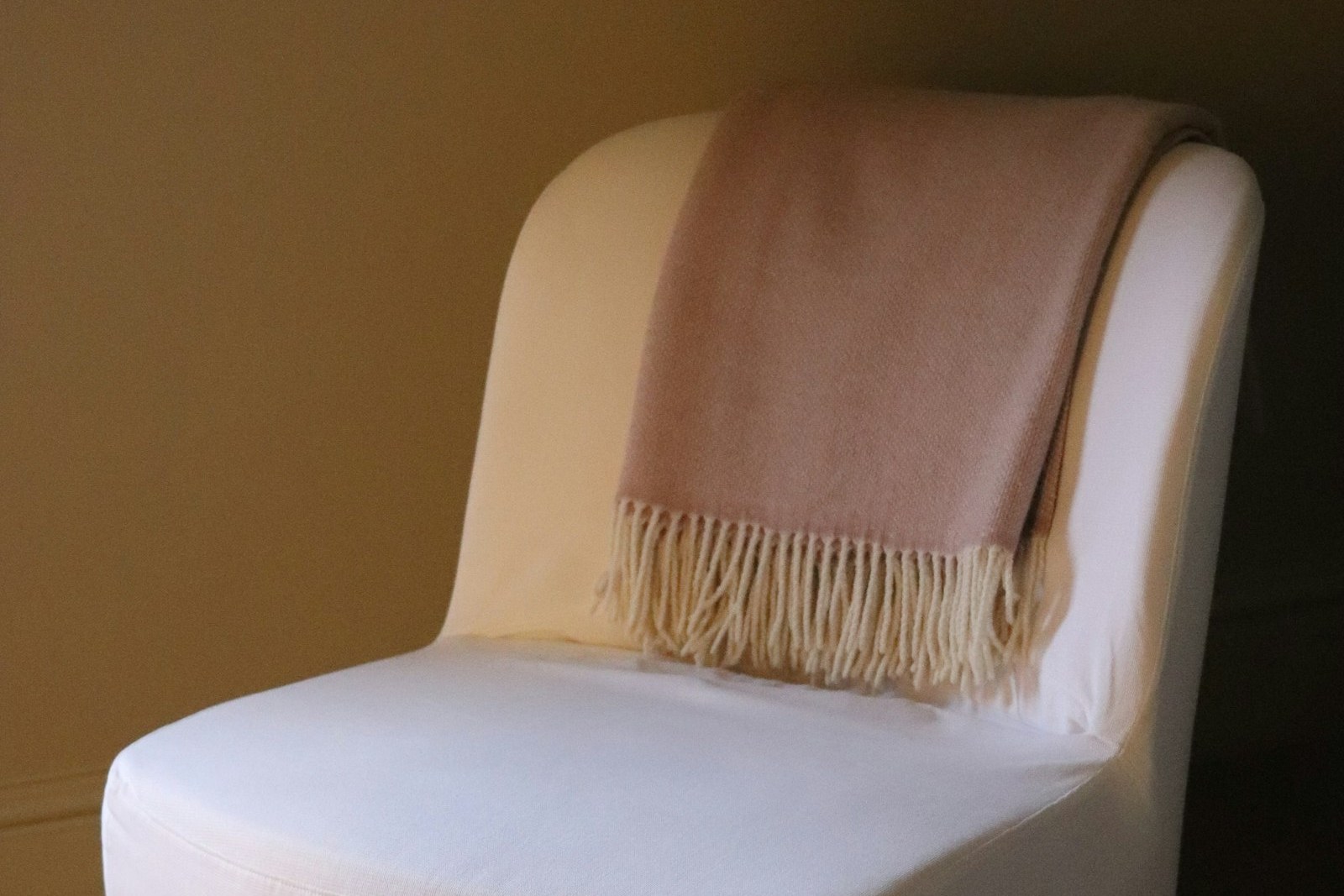 White armchair with a pink throw blanket draped over the back