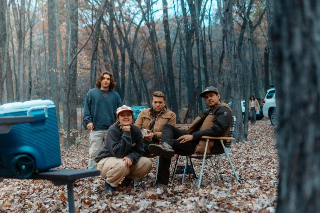 Blue wheeled cooler at a campsite with friends sitting in camp chairs