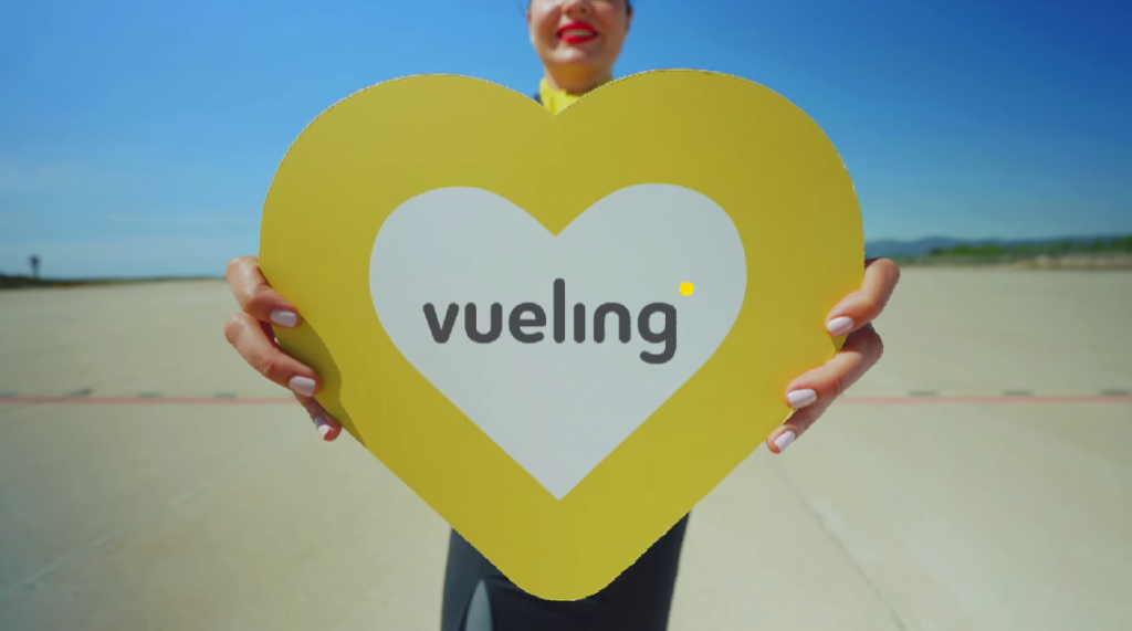 woman with yellow heart-shaped sign in hand with vueling logo