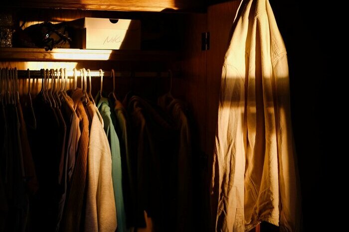 A closet rail with shirts and jackets hanging in a row