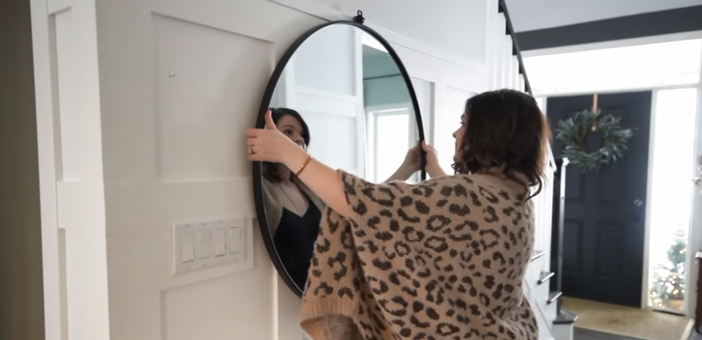 woman placing a mirror in a living room