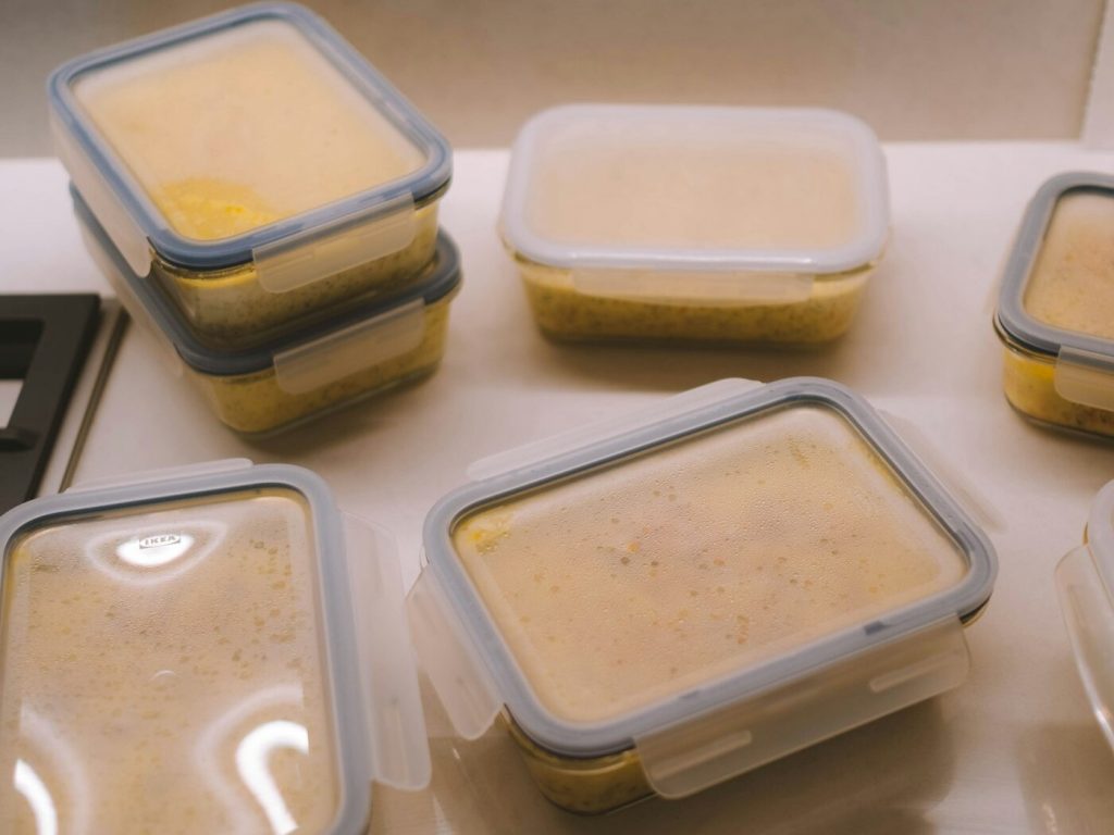 Small plastic containers filled with portions of soup cooling on a counter