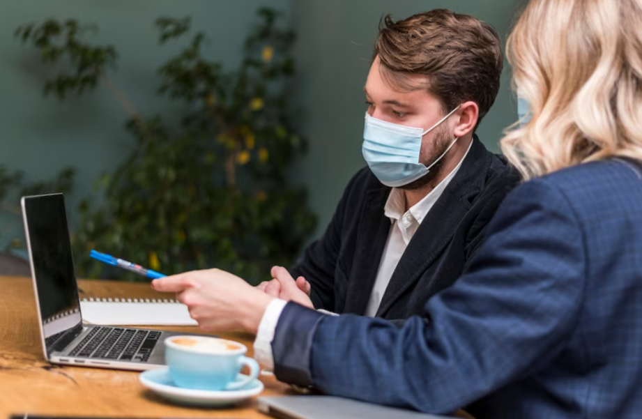 man and woman talking about a new project while wearing medical masks

