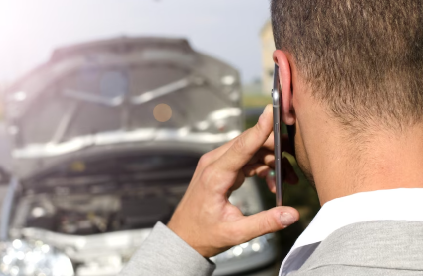 Man standing by the broken vehicle calling tow service