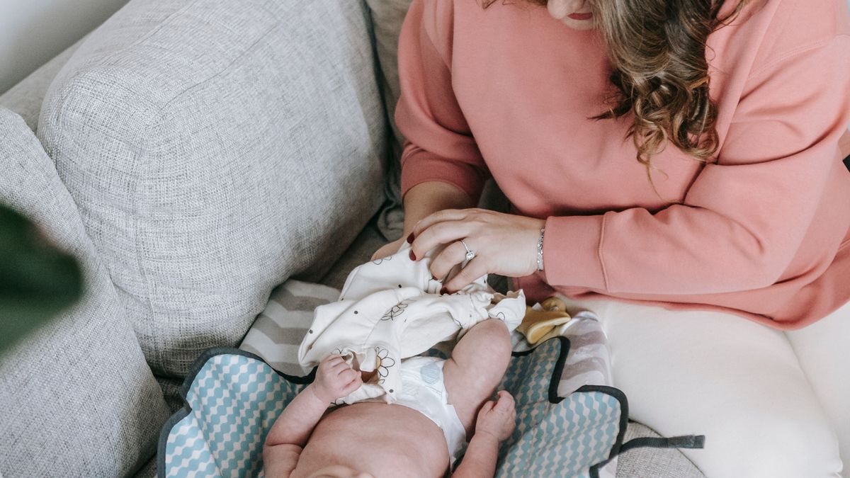 Stock photo: a parent changing a baby on a changing mat at home
