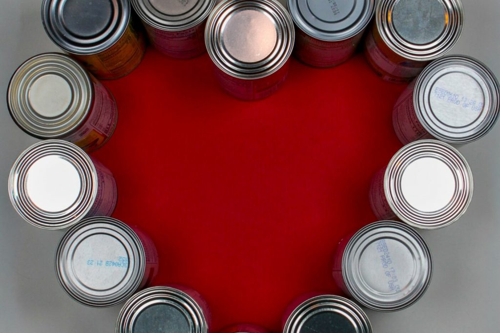 Unlabeled can tops arranged in a heart shape on a red background