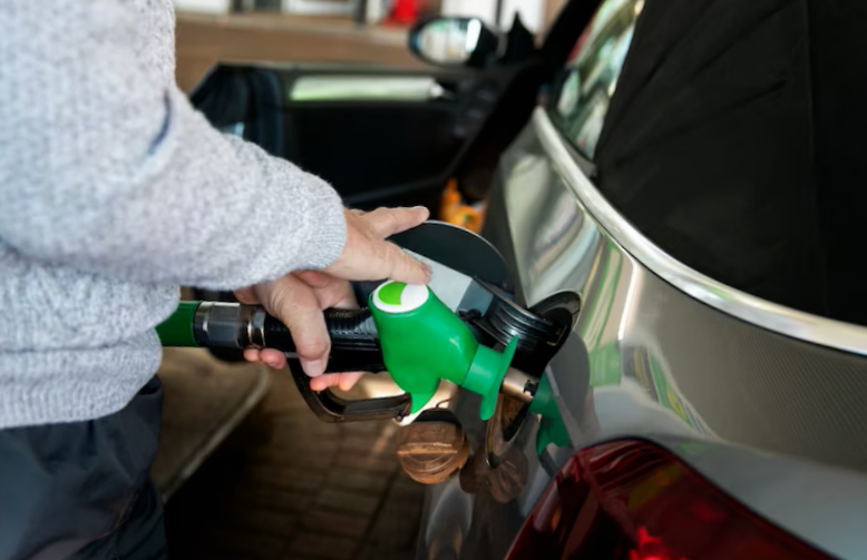 close up hand pumping gas in car