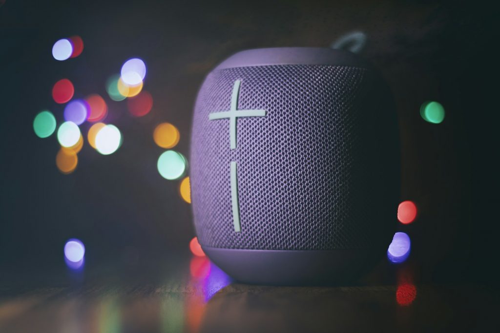 Round portable speaker on a table with colorful lights in the background