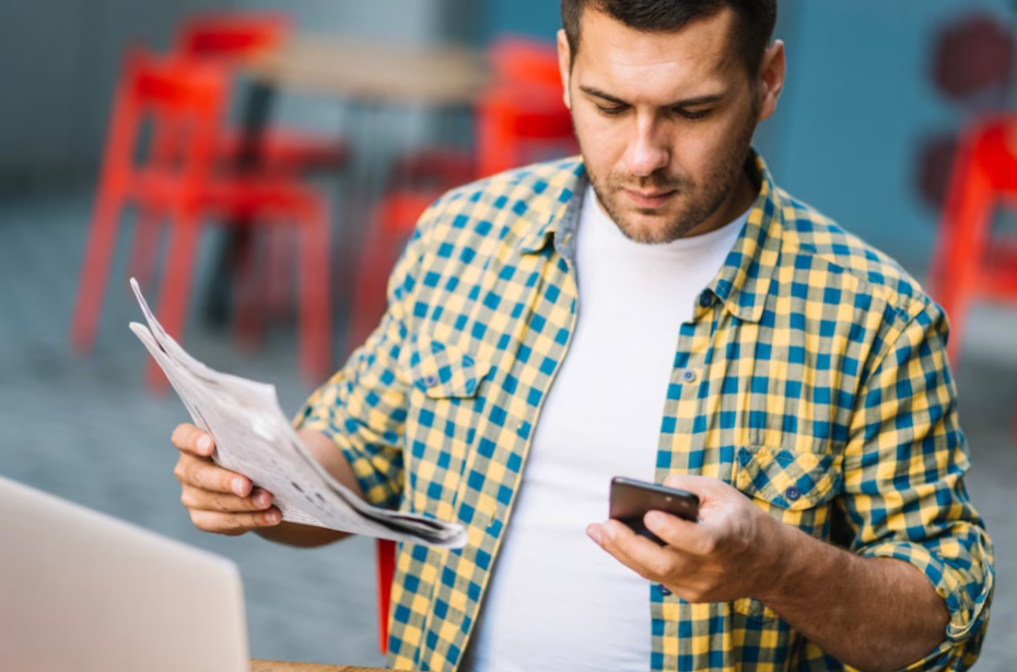 Man posing with phone and newspaper
