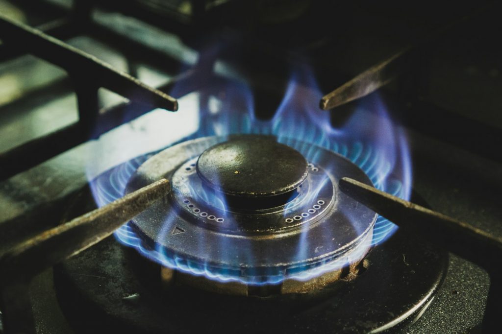 Blue flames burning on a gas stove burner under a cast iron grate