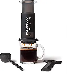 AeroPress Original coffee press with scoop, stirrer and a filled glass mug