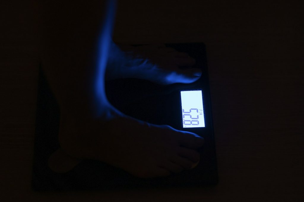Bare feet on a dark digital bathroom scale with a glowing display