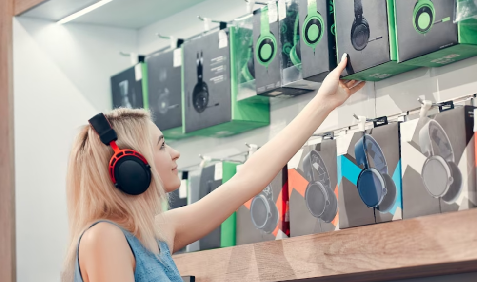 Beautiful smiling girl is testing new headphones in the electronics store.