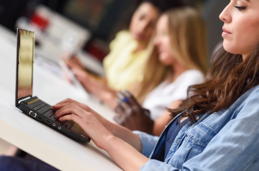 Young woman studying with laptop computer on white desk.