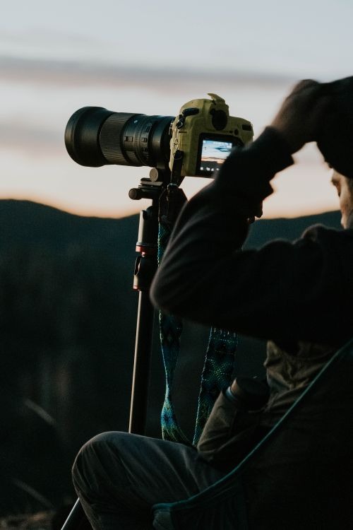 Stock photograph of a photographer using a camera on a tripod, not a listed camera