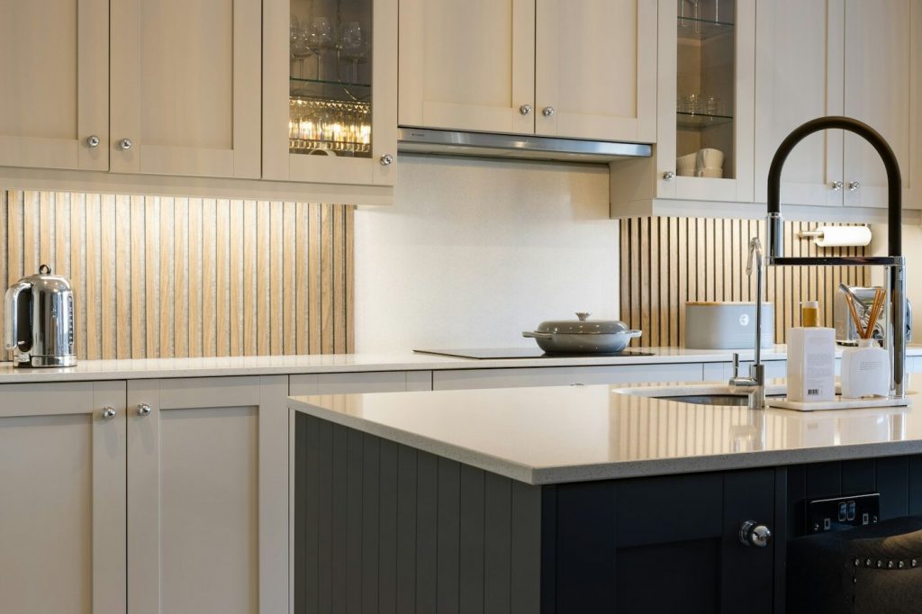 A kitchen with tall cream cabinets reaching toward the ceiling and a dark island
