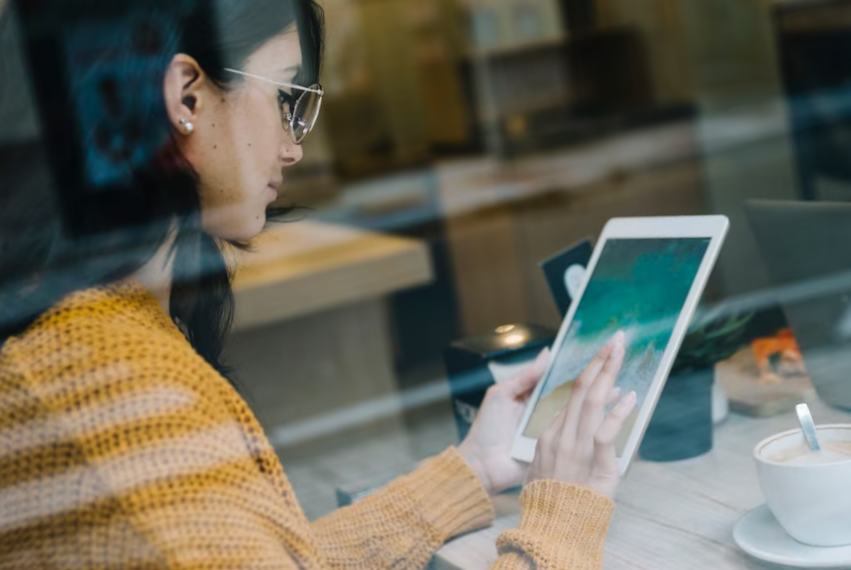 Woman with coffee tapping tablet screen